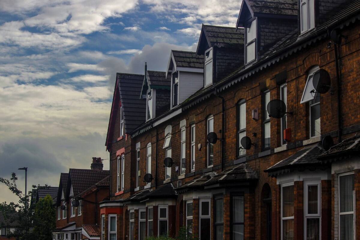 Row of red brick terraced houses in a UK suburb under a cloudy sky