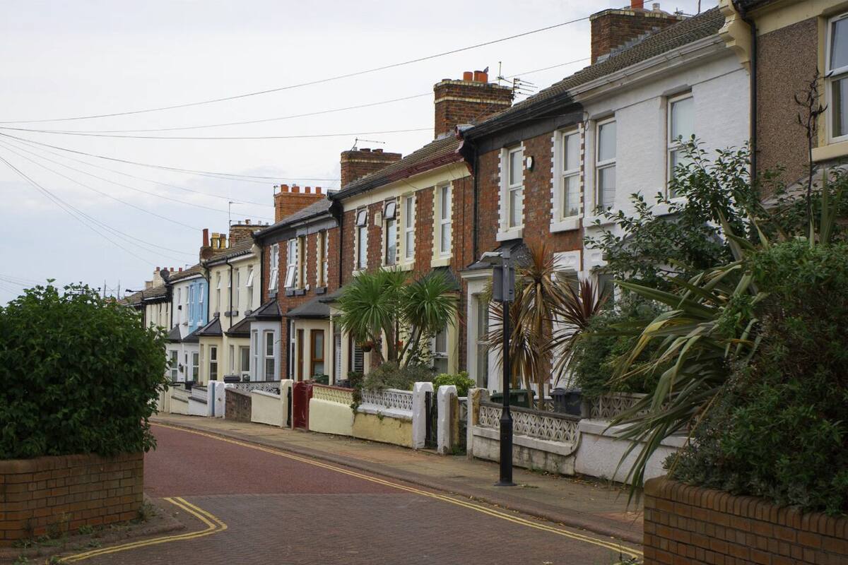 Quiet UK residential street lined with brick terraced houses and front gardens